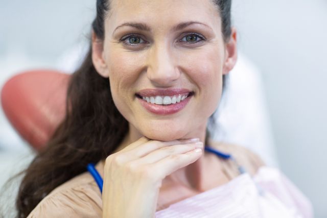 Portrait of smiling female patient sitting on dentist chair at dental clinic