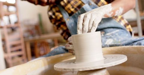 Focused Potter Molding Clay on Wheel in Studio Workshop