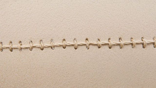 Horizontal twine stitching on beige suede seam, macro texture background for design