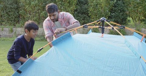 Father and son camping adventure with pop-up tent assembly