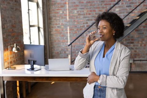 African American Businesswoman Drinking Water in Modern Office