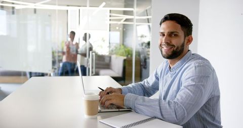 Smiling Professional Man Working on Laptop in Modern Office Environment