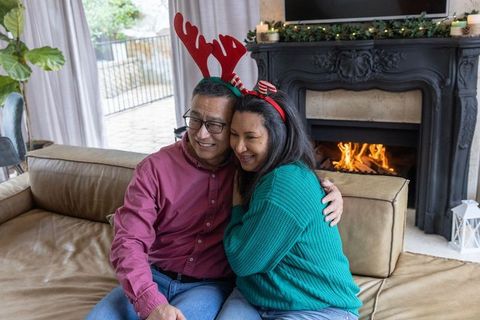 Couple Embracing by Fireplace with Reindeer Antlers During Holidays