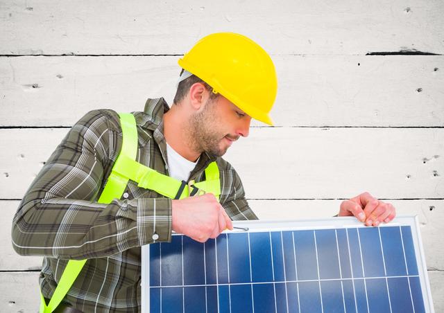 Technician wearing hard hat and safety gear installing solar panel. Ideal for content related to renewable energy, sustainable practices, green technology, and environmental conservation. Useful for articles, blogs, and advertisements promoting solar energy solutions and eco-friendly construction.