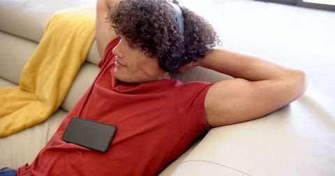 Young Man Relaxing on Sofa with Headphones and Smartphone