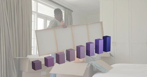 Couple carrying large canvas and unpacking boxes in sunlit bedroom for home decor reveal