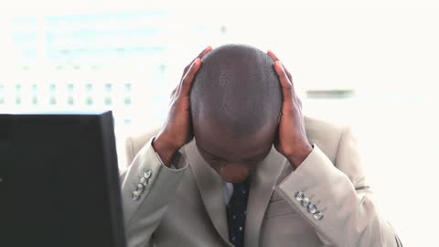 Stressed Businessman Rubbing Head at Office Desk