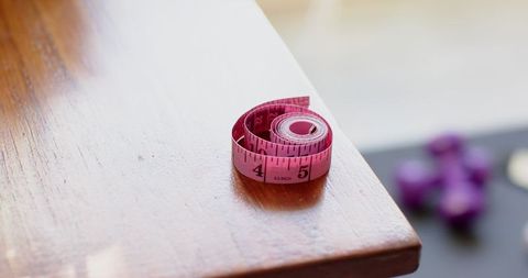 Pink Measuring Tape and Dumbbells on Wooden Tabletop Inspired by Wellness