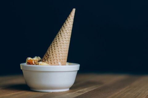 Tilted ice cream cone in bowl on wooden table