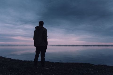 Silhouette of Person Gazing Over Serene Twilight Lake