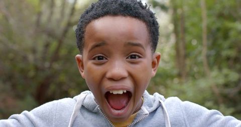 African american boy making surprised excited face outdoors closeup portrait