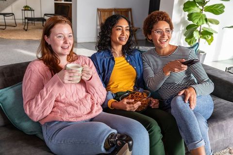 Diverse Friends Relaxing and Sharing Snacks in Contemporary Living Room
