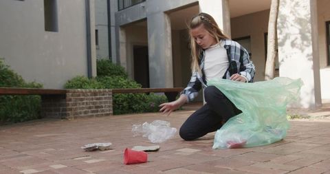 Young volunteer collecting litter in urban courtyard