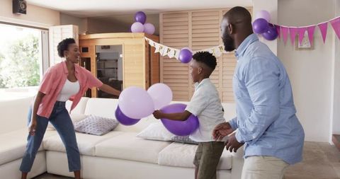 African American Family Celebrating Birthday with Purple Balloons in Sunlit Living Room