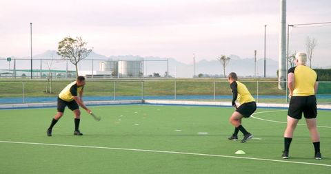 Team athletes practicing field hockey drills on turf