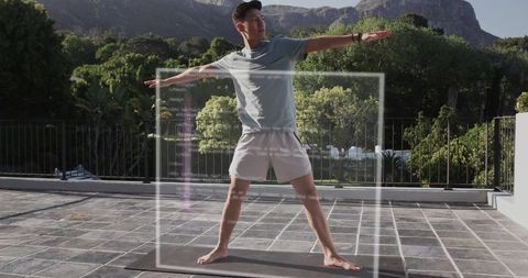 Asian man practicing yoga on terrace with code overlay blending fitness and technology