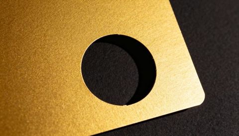 Textured gold die-cut card with circular hole casting dramatic shadow