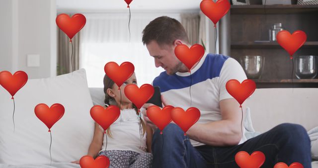 Image of heart balloons over caucasian father and daughter using smartphone on sofa. family, love and communication technology concept digitally generated image.