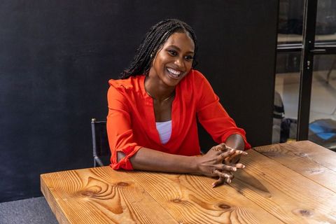 Confident African American Woman In Red Blouse At Wooden Desk