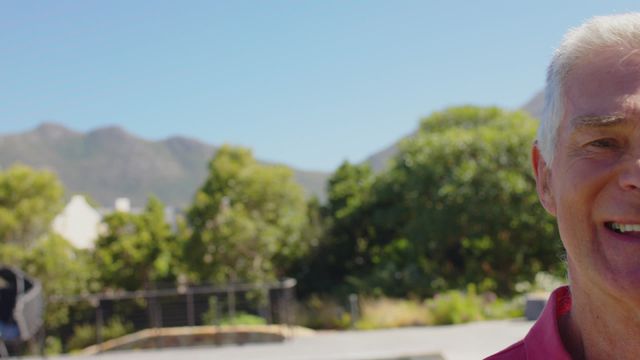 The video shows a senior Caucasian man enjoying a sunny day in a lush garden, exhibiting a cheerful demeanor. Ideal for use in promoting retirement communities, senior healthcare services, lifestyle blogs focused on aging, or advertising any product targeting older adults' well-being and happiness.