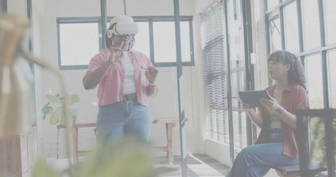 Woman exploring virtual interface with vr headset while colleague using tablet in office