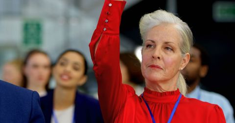 Senior businesswoman raising hand in interactive seminar session