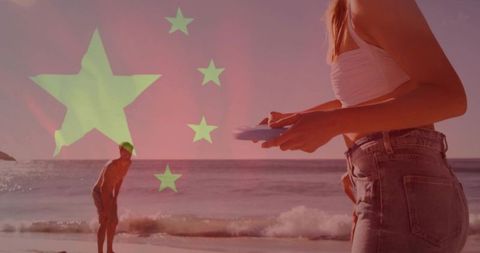 Woman holding frisbee on beach wearing crop top and jeans with china flag overlay