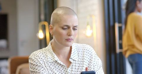 Shaved-head professional checking smartphone in modern coworking lounge with focused concern