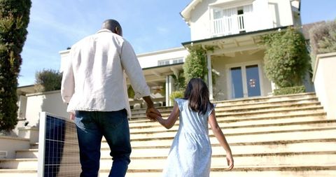 Father and Daughter Walking Towards Dream Home Holding Hands