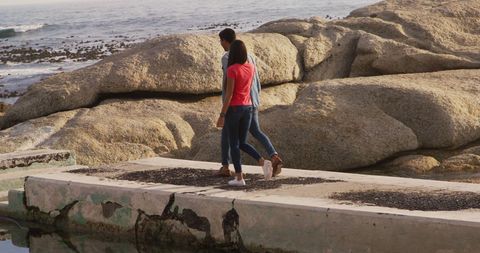 Diverse Couple Strolling on Seaside Pier in Casual Attire