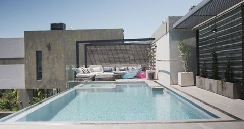 Luxury rooftop pool with pergola lounge, cushioned seating, planters and colorful floats