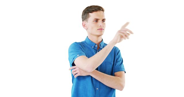 Young man in mid-20s wearing blue shirt, confidently pointing with right hand. Set against white background. Ideal for concepts of decision-making, clarity, and presenting ideas in professional or educational settings.