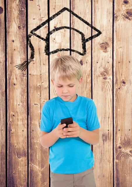 Young boy using a smartphone with a graduation cap sketch above his head on a wooden background. Ideal for educational technology, future learning, and child development themes. Can be used in articles, blogs, and advertisements related to children's education, digital learning tools, and the impact of technology on youth.