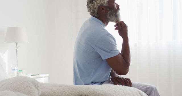 Pensive Elderly Man Sitting on Bed in White Room - Download Free Stock Images Pikwizard.com