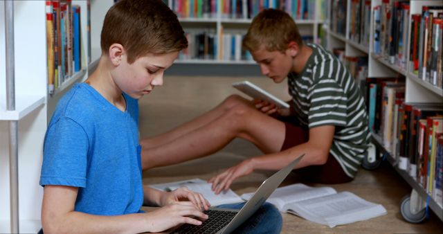 Teenage boys utilize technology amidst books in a library, emphasizing modern education. - Download Free Stock Photos Pikwizard.com