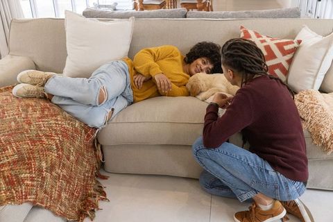 African american couple relaxing on beige sofa while petting golden puppy at home