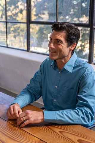 Man in blue shirt sitting at office table by sunny window