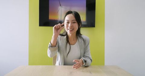 Asian businesswoman presenting small size gesture during office meeting with green accent
