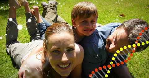 Young family lying on sunlit lawn with dna helix overlay representing genetics and health