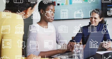 Business women collaborating over laptop showing financial icons and charts