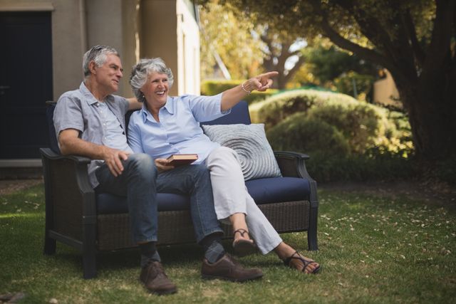 Senior couple enjoying a relaxed moment on a couch in their backyard. Ideal for use in advertisements or articles related to retirement, senior living, outdoor activities, and family bonding.