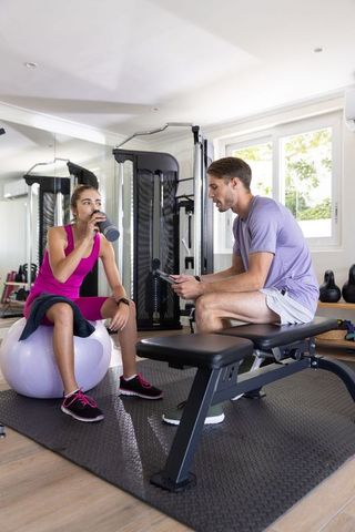 Personal trainer guiding client with tablet in home gym setting