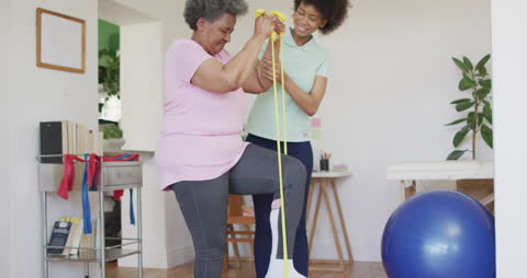 Senior Woman Practicing Physical Therapy with Supportive Therapist at Home