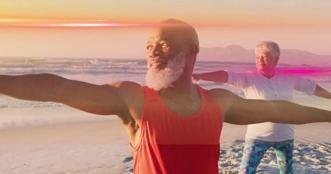Senior couple practicing yoga warrior pose on sunset beach