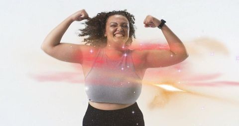 Confident curvy woman flexing in activewear wearing smartwatch, radiant energy glow
