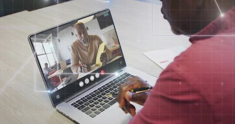 Holding Pen and Taking Notes During Virtual Meeting on Laptop with Remote Presenter Holding Folder