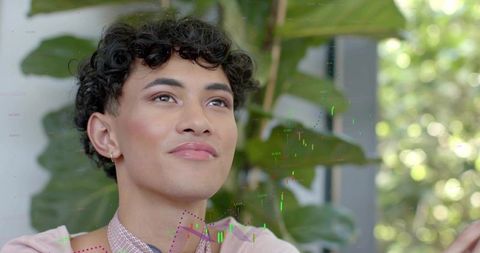 Young male looking upward with hopeful expression wearing pastel pink top and hoop earring