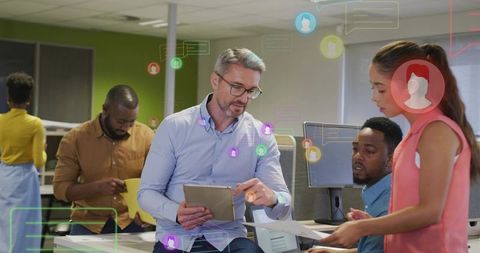 Mature manager demonstrating tablet-led collaboration with diverse team in modern office