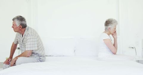 Senior couple sitting apart after argument on bed