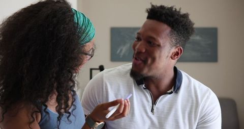 Excited couple celebrating pregnancy announcement at home